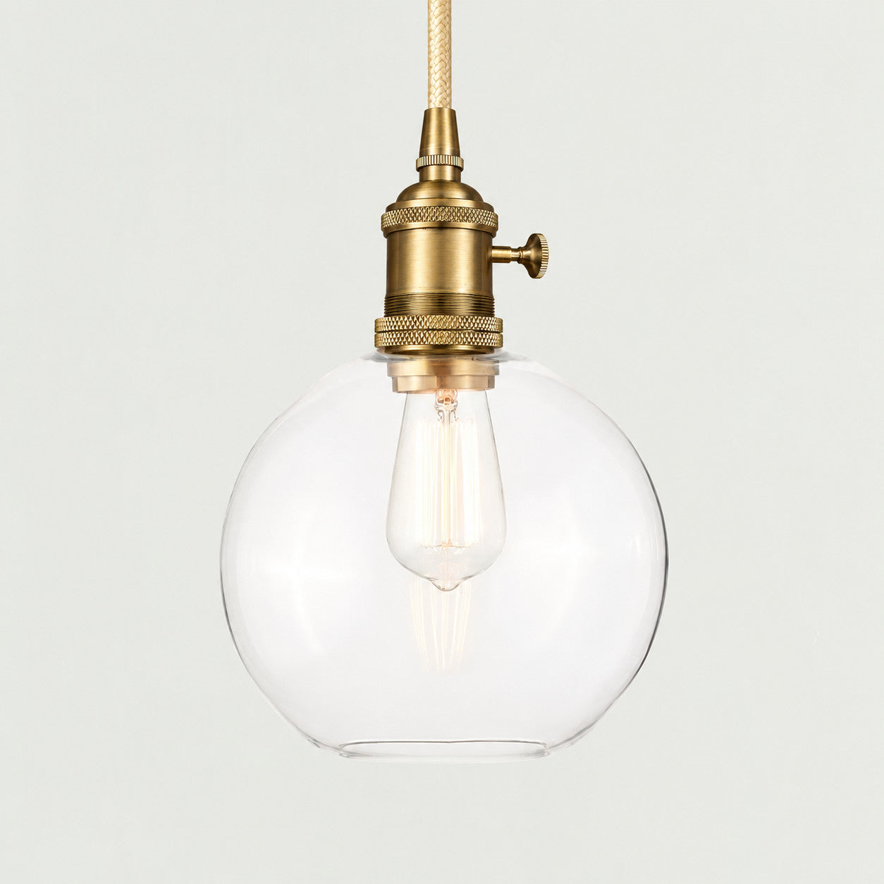 Brass(Small) clear glass globe pendant on a plain background