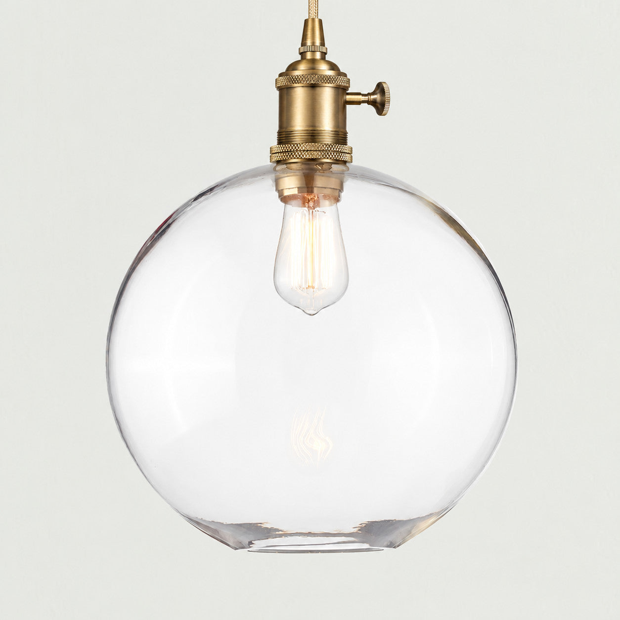 Brass(Large) clear glass globe pendant on a plain background